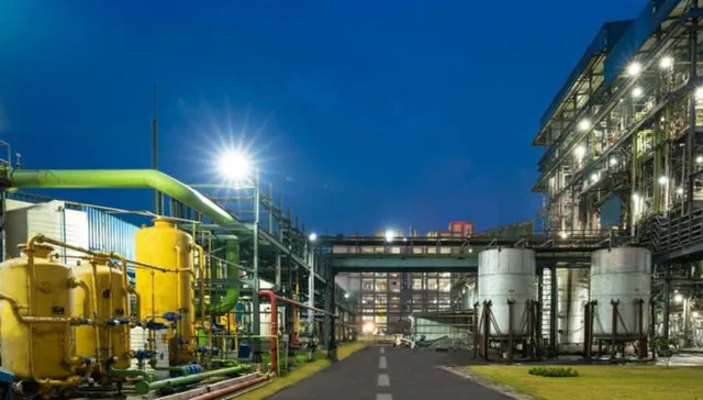 Chemical plant at night with yellow storage tanks, silos and pipe racks